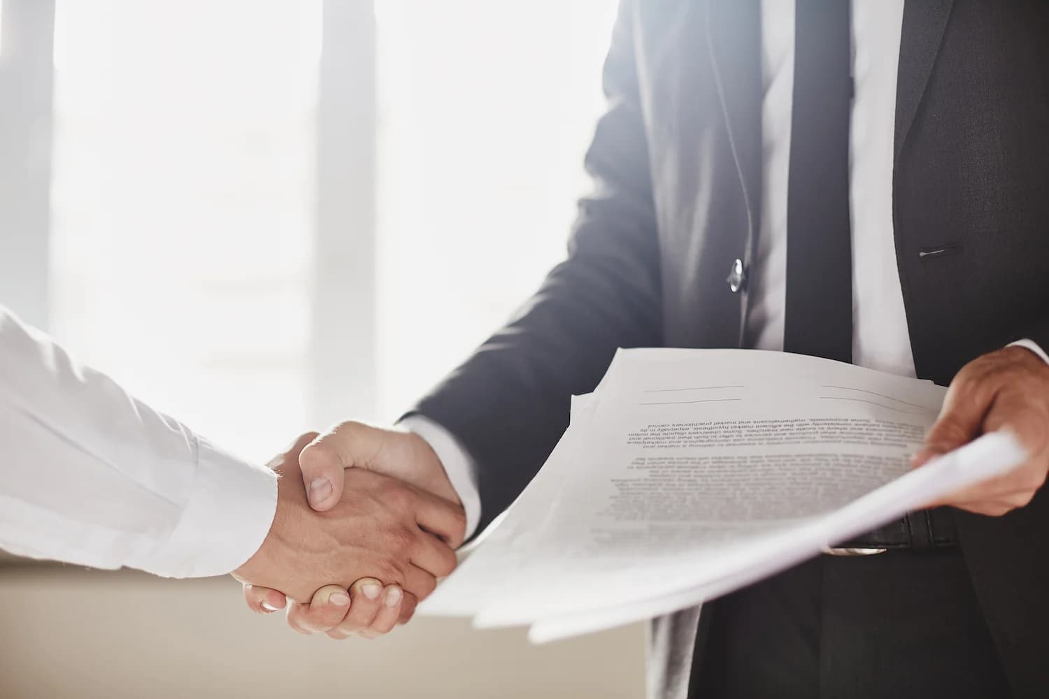 Two businessmen signing documents illustrating commercial contract management.
